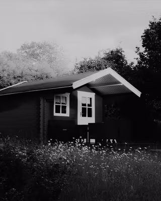 A red wooden cabin in a summer garden with the Acros look, the base of the Silver Street recipe