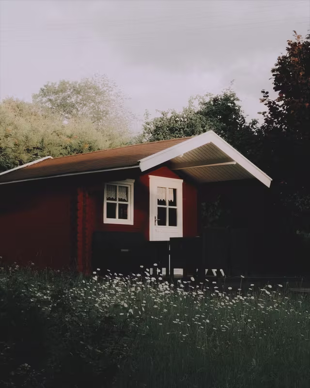 A red wooden cabin in a summer garden with the Autochrome look