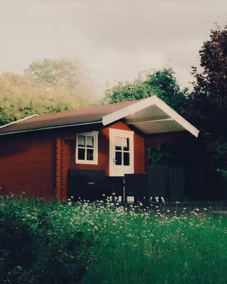 A red wooden cabin in a summer garden with the Cinestill 800T look, the base of the Neon Night recipe