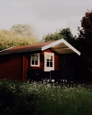 A red wooden cabin in a summer garden with the Classic Chrome look, the base of the Street Chrome recipe