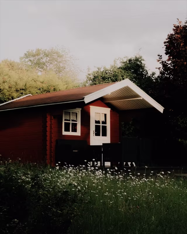 A red wooden cabin in a summer garden with the Classic Chrome look