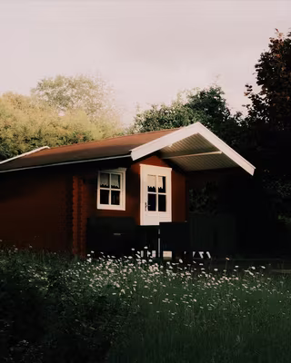 A red wooden cabin in a summer garden with the Classic Neg look, the base of the Faded Negative recipe