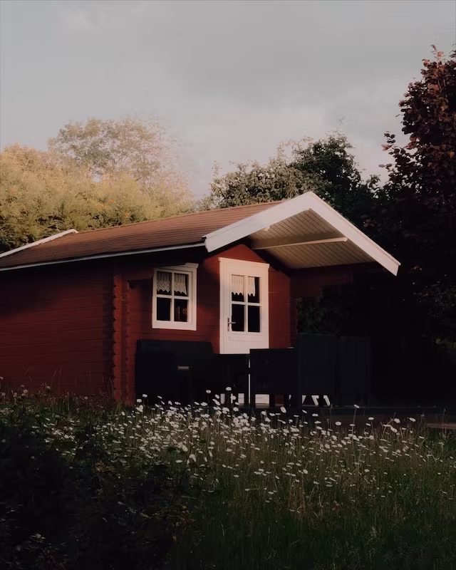 A red wooden cabin in a summer garden with the Cyberpunk look
