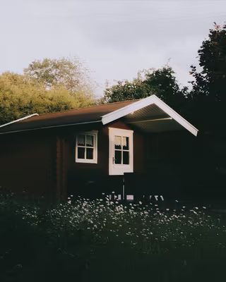 A red wooden cabin in a summer garden with the Polaroid look, the base of the Instant Snapshot recipe